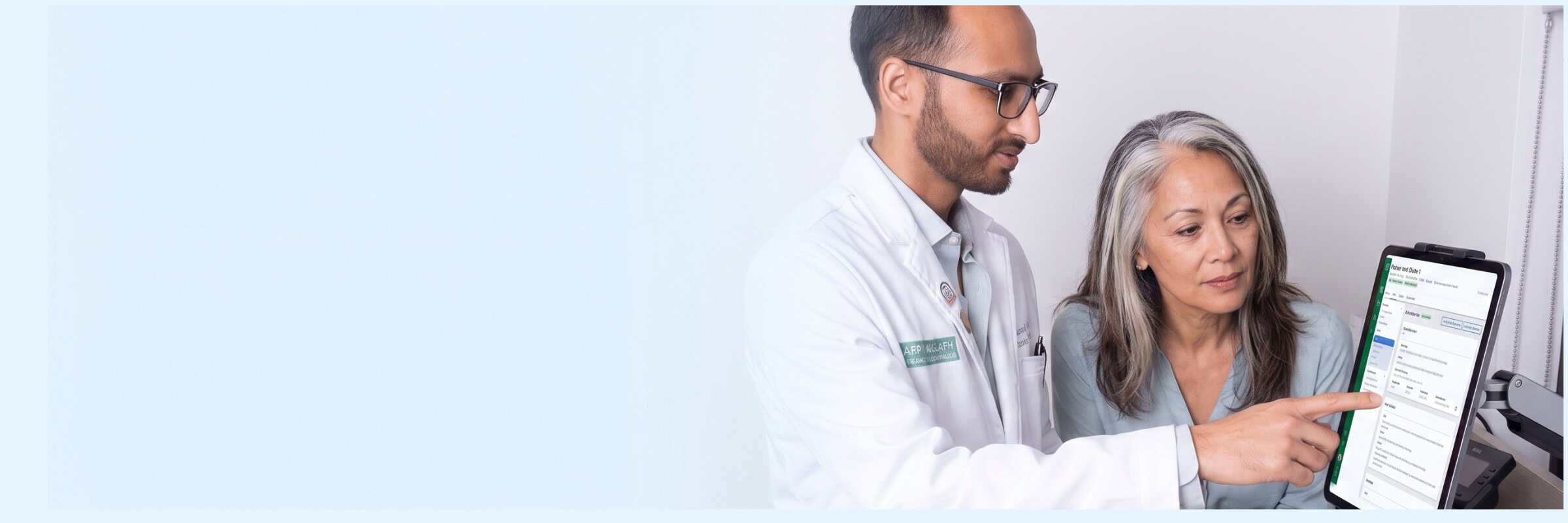 Physician reviewing CCM care data on a monitor with an older patient during an exam-room visit