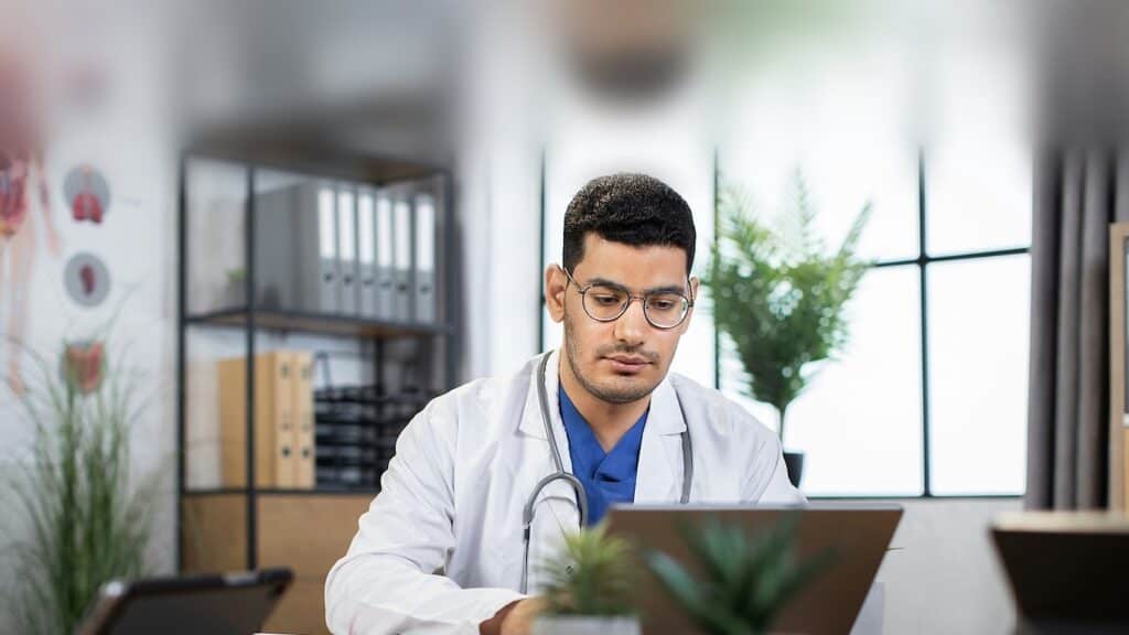 Physician reviewing chronic care management documentation on a laptop