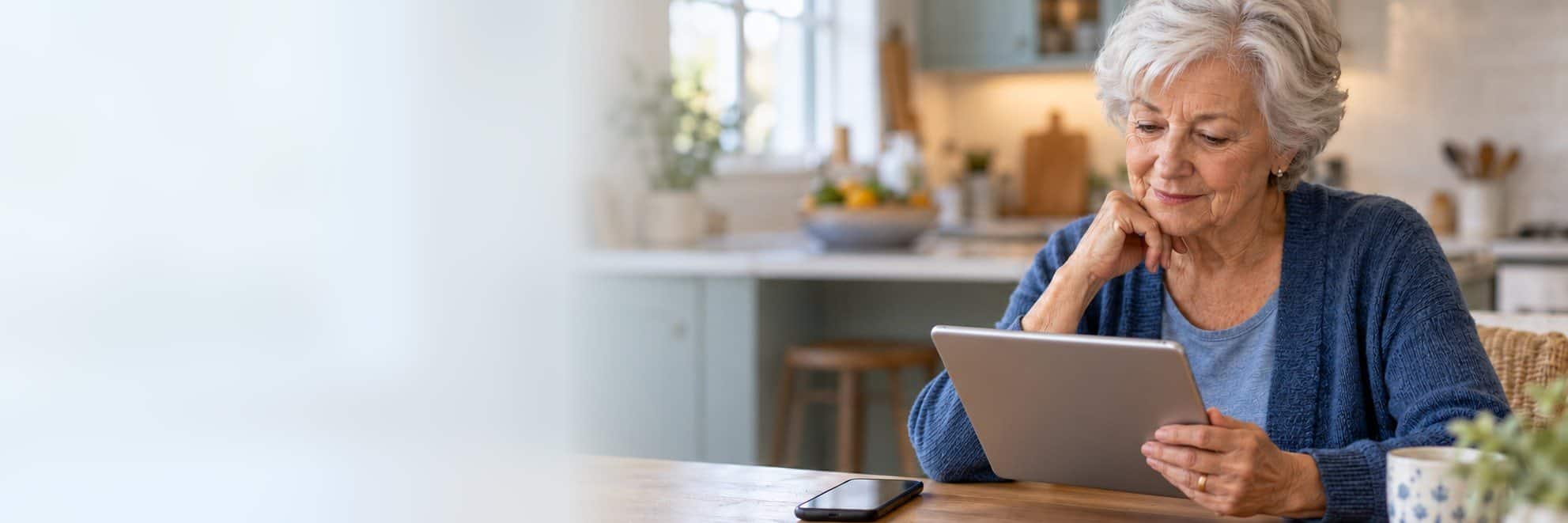 Older woman at her kitchen table reviewing RPM and CCM care updates on a tablet